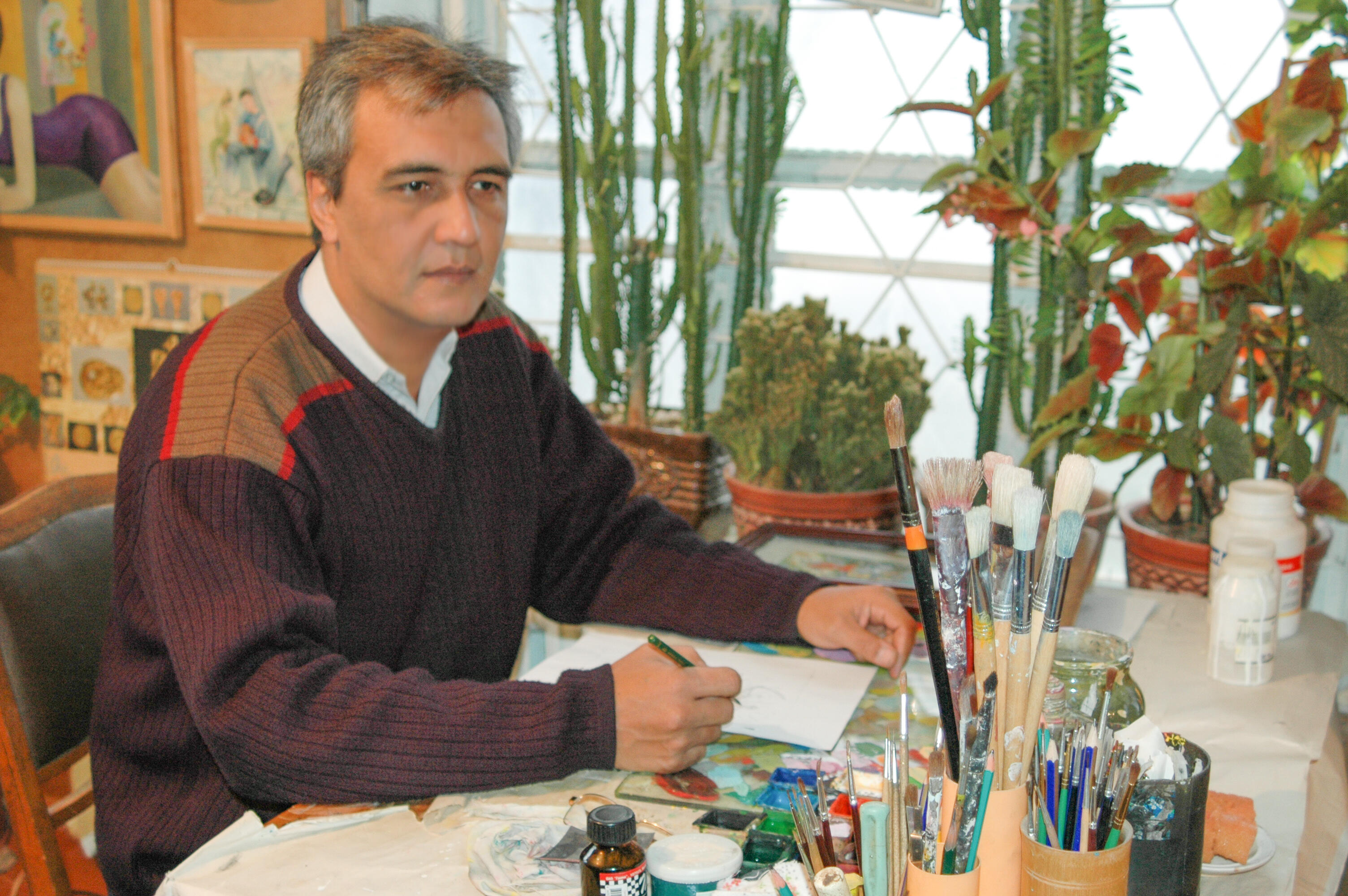 Olim Kamolzoda is the Honoured Artist of the Republic of Tajikistan. Photo of Olim Kamolzoda sitting at the desk in his workshop. He is the Honoured Artist of the Republic of Tajikistan, a Member of the Union of Artists of the Republic of Tajikistan, and a Specialist of the Miniature Art. Studying the specifics of the work